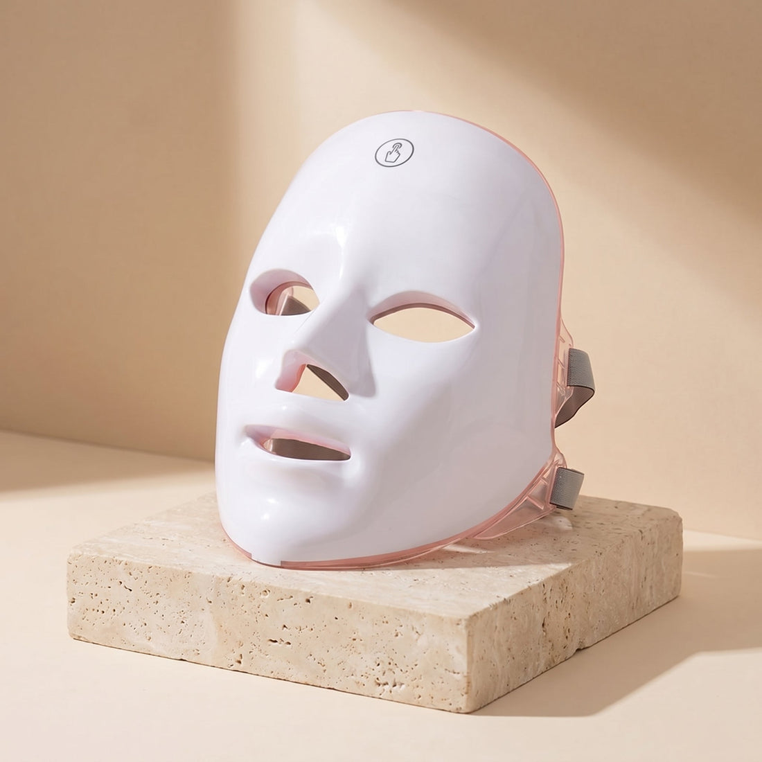 GlowZen LED facial mask displayed upright on a travertine stone pedestal