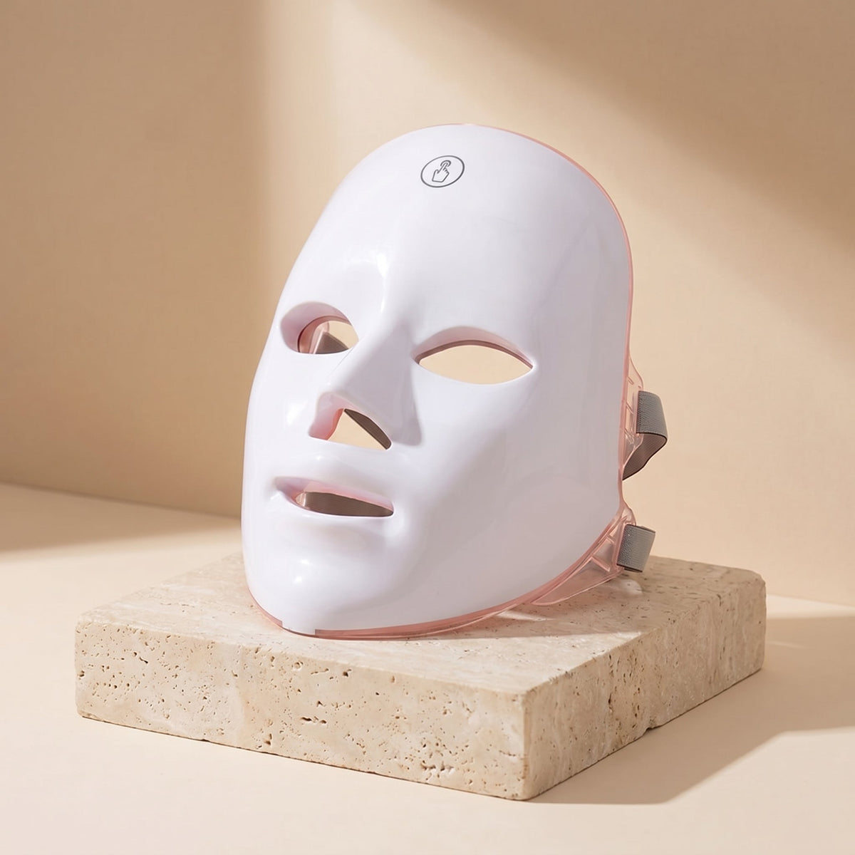 GlowZen LED facial mask displayed upright on a travertine stone pedestal