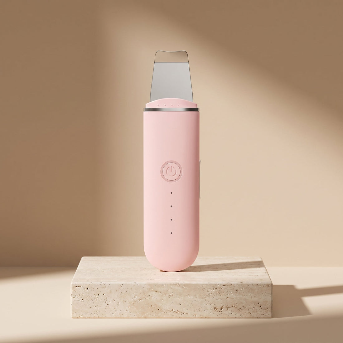 PoreZen sonic skin scrubber in pink on a travertine stone pedestal