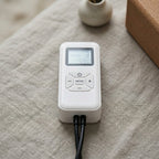 Close-up of the LegZen white handheld remote with LCD screen and mode buttons
