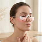 Woman wearing the LumiZen under-eye device with soft red light glow