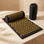 AcuZen acupressure mat pillow and bag in gold on a travertine pedestal