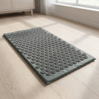 Gray AcuZen mat lying flat and unrolled on a wood floor