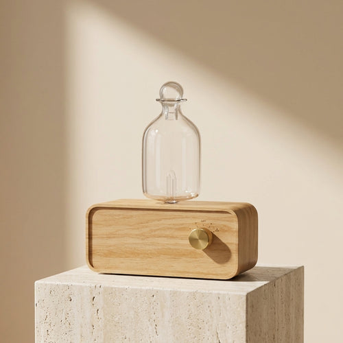 Zenyzen AromaZen nebulizing diffuser with glass bottle on a travertine pedestal