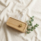 AromaZen wood and glass diffuser on cream linen fabric with eucalyptus sprig