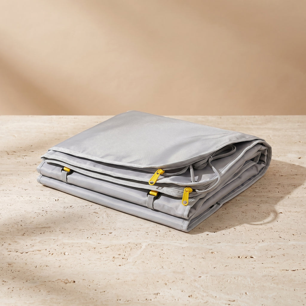 CocoonZen infrared sauna blanket in silver-gray folded on travertine surface
