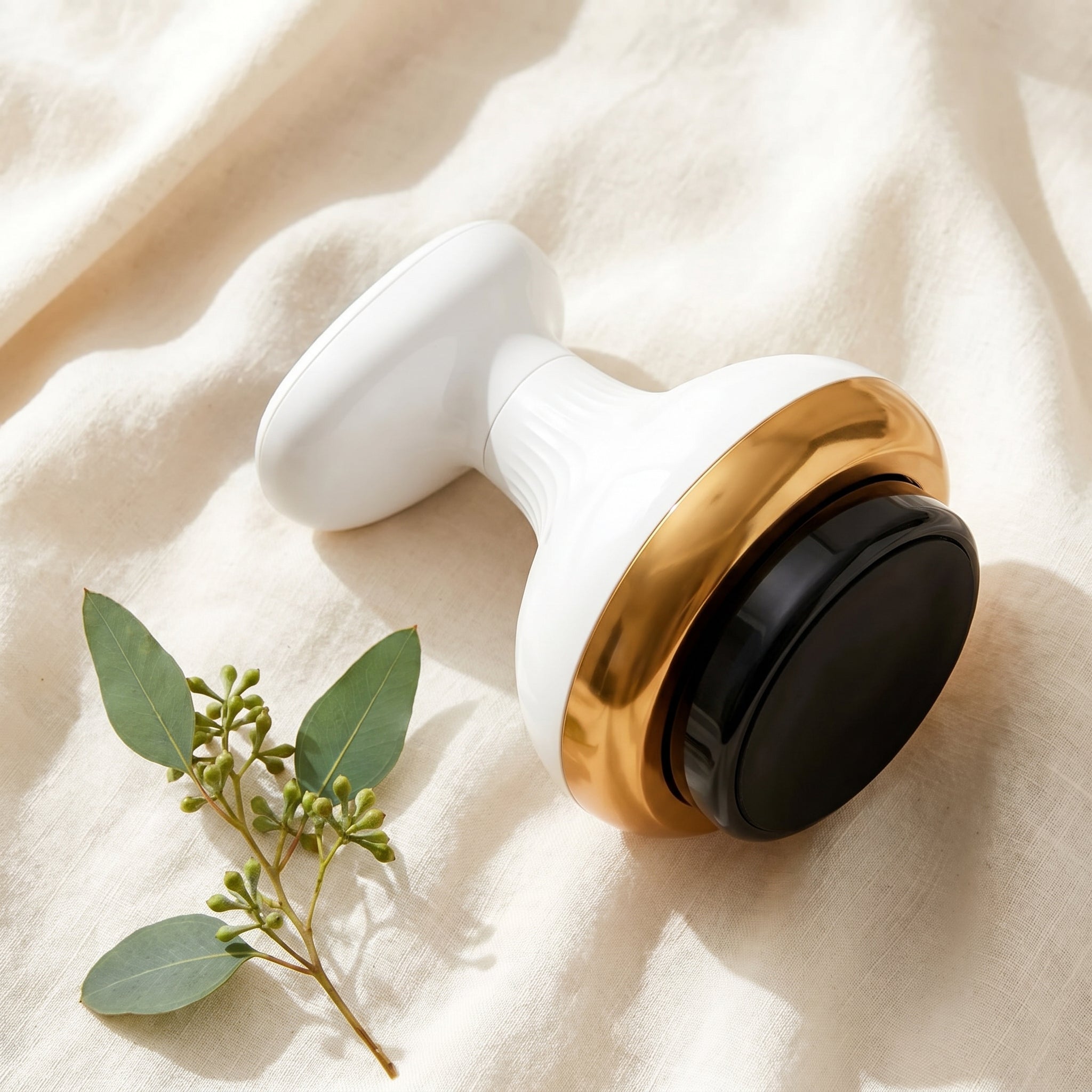 ContourZen massager resting on cream linen beside a eucalyptus sprig