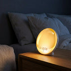DawnZen alarm clock glowing amber on a wooden nightstand in a cozy bedroom setting