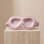 DreamZen pink contoured silk sleep mask on a travertine pedestal