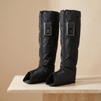 FlowZen air compression recovery boots in black on a travertine pedestal
