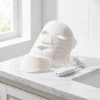 White LED neck and décolleté mask on a marble vanity surface with soft light