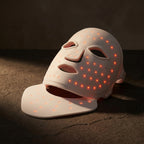 GlowZen Neck LED mask on dark charcoal surface with dramatic side lighting