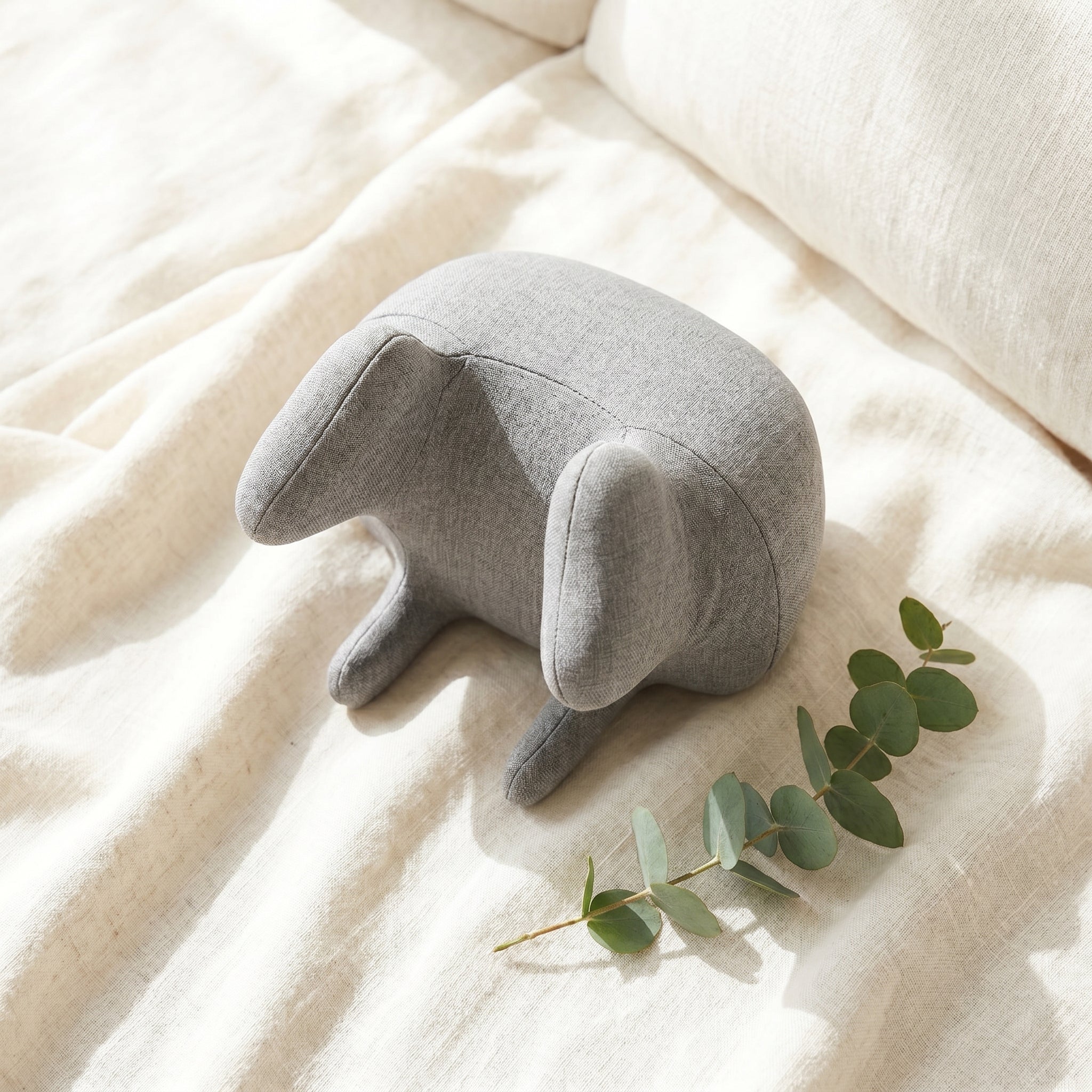 KneadZen shiatsu cushion on cream linen fabric beside eucalyptus sprig