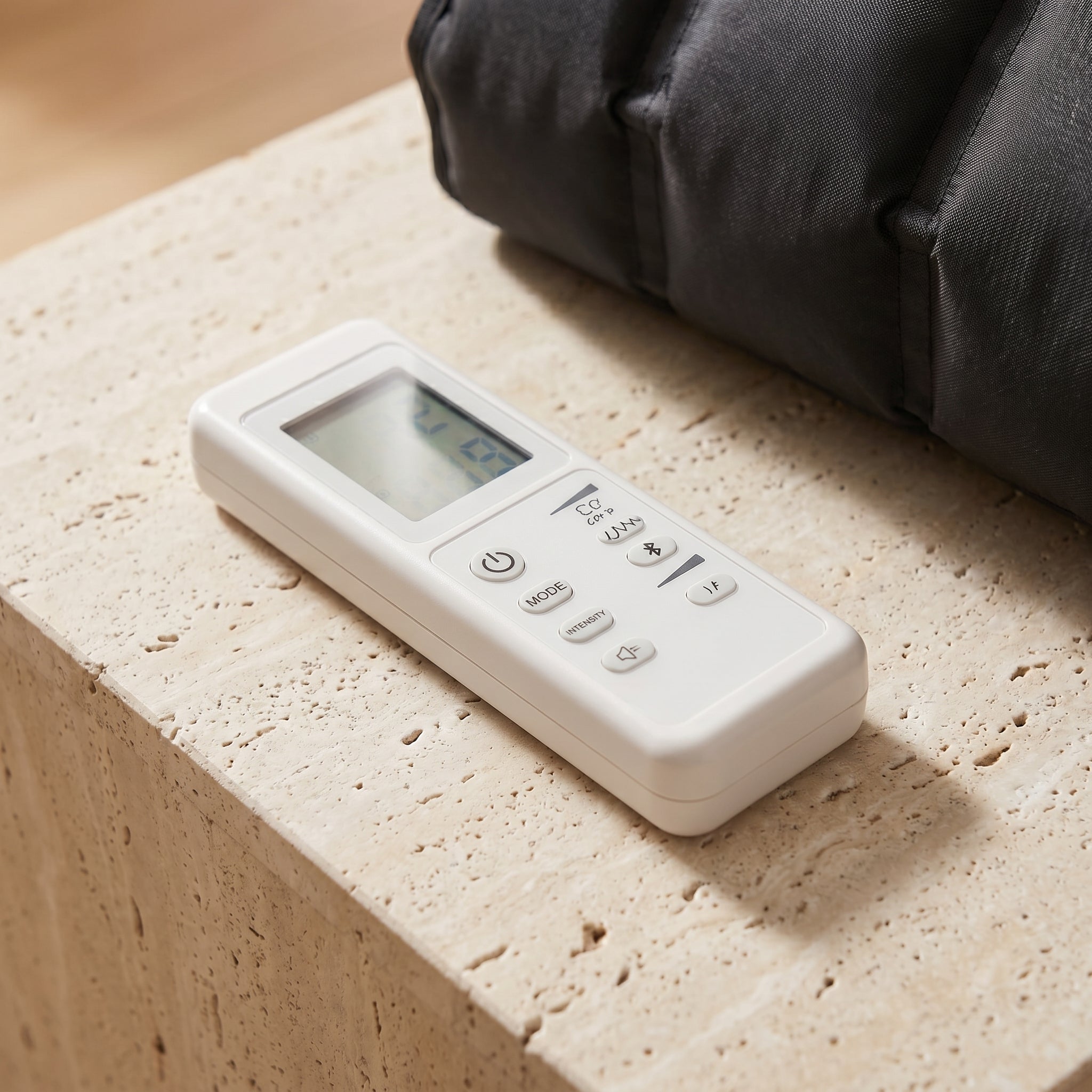 Close-up of LegZen remote controller on travertine with black boot beside it