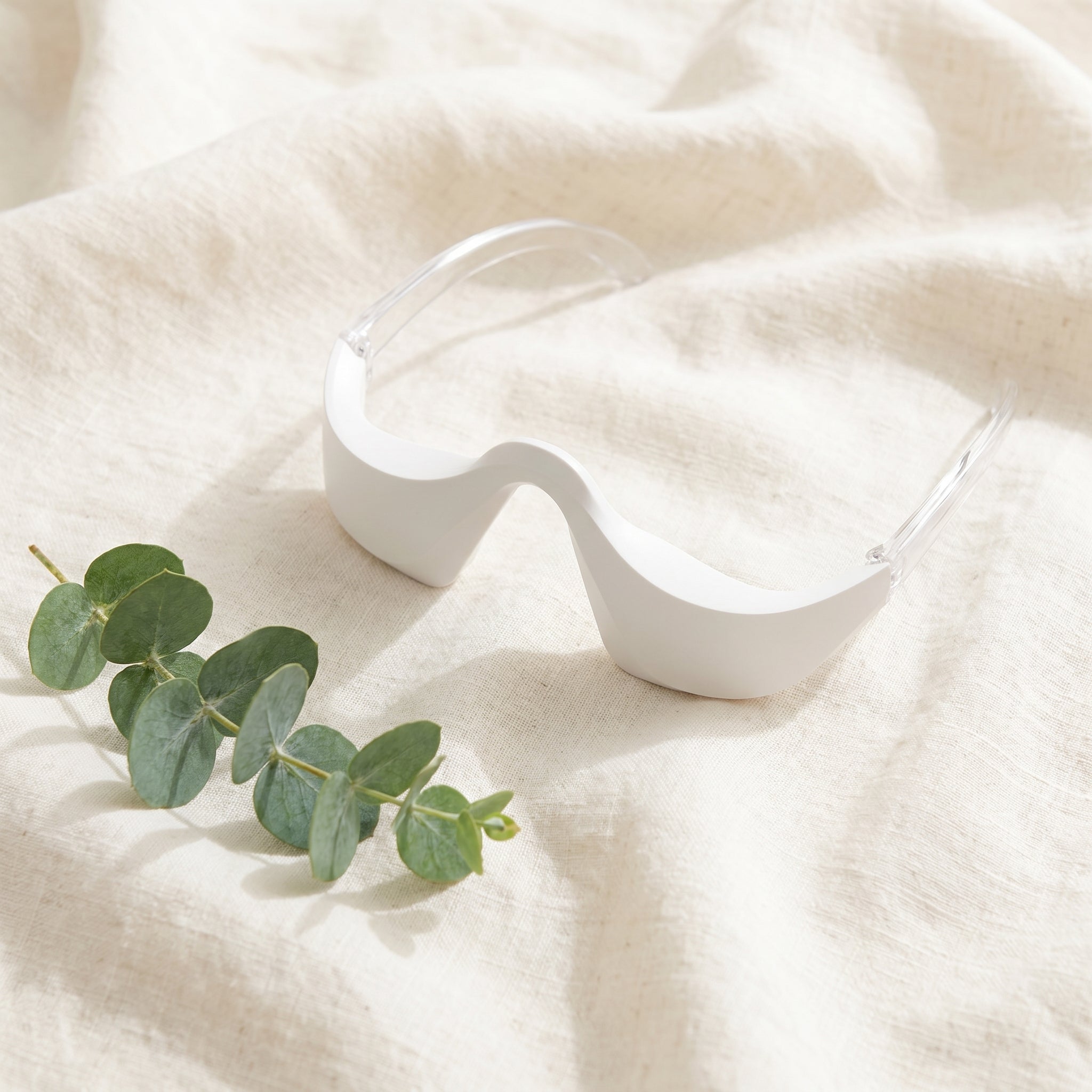 LumiZen glasses-style eye device on cream linen with eucalyptus