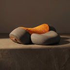PillowZen neck pillow on dark stone with dramatic side lighting and shadow