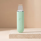 PoreZen scrubber in mint green on a travertine block with beige backdrop