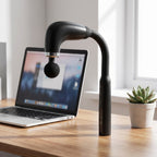 Black massage gun standing on a wooden home-office desk