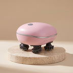 Pink ScalpZen electric head massager on a travertine stone pedestal