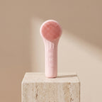 SonicZen brush in pink shown upright on a travertine stone block