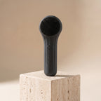 SonicZen brush in charcoal black on a travertine pedestal in warm light